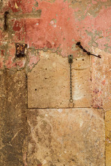 Italy, Basilicata, Province of Matera, Matera. Detail of peeling orange stuco and stone wall.