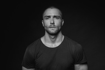 Black and White Muscle strong beautiful stripped male model with black t-shirt in denim blue jeans on black isolated font background