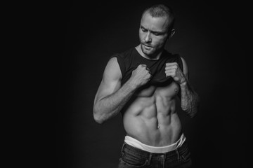 Naklejka na ściany i meble Black and White Muscle strong beautiful stripped male model with black t-shirt in denim blue jeans on black isolated font background