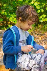 Cute white boy eats porridge from a bowl on a picnic outdoors