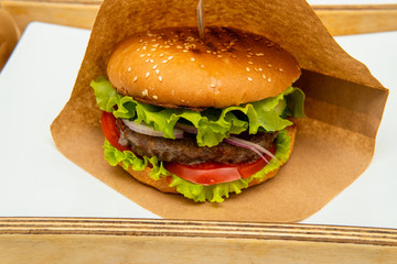 Craft beef burgers with vegetables. Delicious fresh homemade burger. Tasty juicy and beautiful burger on a paper bag