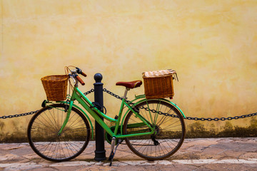 Fototapeta na wymiar Italy, Apulia, Province of Lecce, Lecce. Women's bicycle, with wicker baskets, propped against a post.