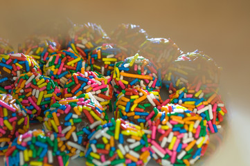 typical brazilian sweet at birthday parties, Brigadeiro, with colorful chocolate sprinkles on white plate