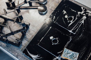 cleaning the kitchen, cleaning a modern gas stove with a sponge and foam.