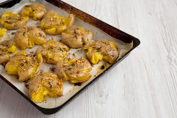 Homemade garlic thyme smashed potatoes on a tray, side view. Copy space.