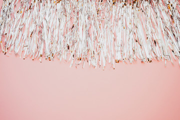 Silver metal foil tinsel strips isolated on pink background, christmas or festive decoration...