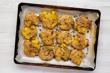 Homemade garlic thyme smashed potatoes on a tray, top view. Flat lay, overhead, from above. Close-up.