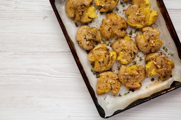 Top view, homemade garlic thyme smashed potatoes on a tray. Flat lay, overhead, from above. Copy space.
