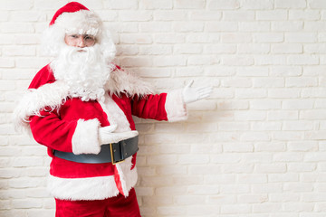 Man in Santa costume gesturing on his left side