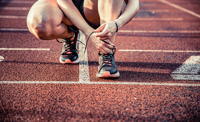 young woman on running track lacing her shoes
