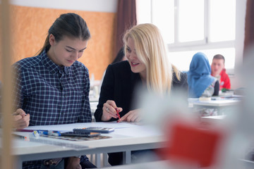 Female Architecture teacher at work. Female professor explain architectural projects to students. Beautiful female university architecture professor explain lessons to multiethnic students.