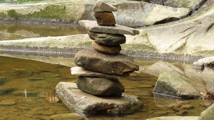 stack of rocks in a peaceful river with other big rocks