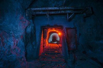 Dark dirty abandoned uranium mine with rusty remnants of railway color illuminated © Mulderphoto