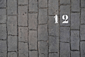 12, number twelve, white stencil number on cobblestone surface.
