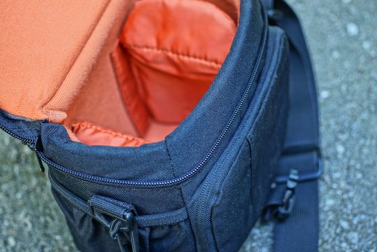 black red camera bag lies on gray asphalt