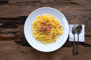 Spaghetti bacon carbonara food delicious put on a white plateon a wooden background from top view.