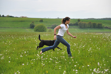 Cute barefoot girl is playing with black dog © VGV