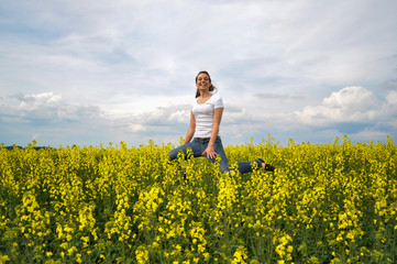 Fototapeta premium Girl Is Jumping In A Blooming Rapeseed Field