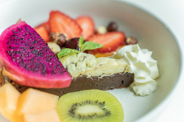 Traditional homemade chocolate cake with mix fruit sweet pastry dessert on white disc.