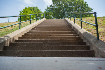 Obraz premium A POV looking up (from the bottom) a tall stone staircase in the city public park.