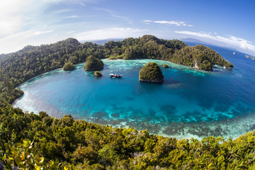 A small ship rests at anchor amid the tranquil seascape in Raja Ampat, Indonesia. This equatorial region is possibly the center for marine biodiversity.