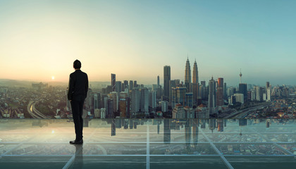 Businessman standing at transparent glass floor on rooftop with city skyline, success and thinking...