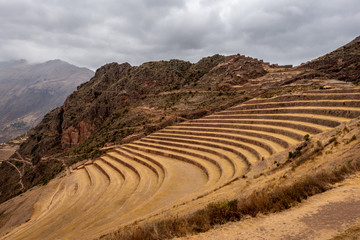 Fototapeta na wymiar The dry rocky mountain sides within the Sacred Valley of Peru are lined with terraced farmland formed from stone that has held in its place for centuries