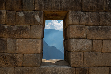 Endless mountains carry on far beyond the weathered stone walls with a glimpse of those that await through a window looking out to the Sacred Valley below on a partially cloudy day