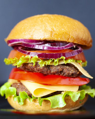 fresh fast food cheeseburger (double burger) with two cutlets, onions, bell peppers, cheese, tomatoes and lettuce