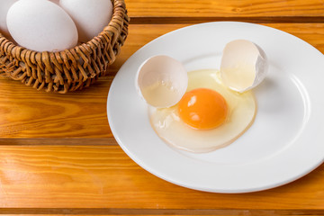 木目の上に割った生卵が殻がお皿の上に置いてある