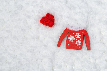 Wooden red jumper and red cap in snow. Christmas decor. Happy New Year 2020 poster or greeting card with copy space. Selective focus.