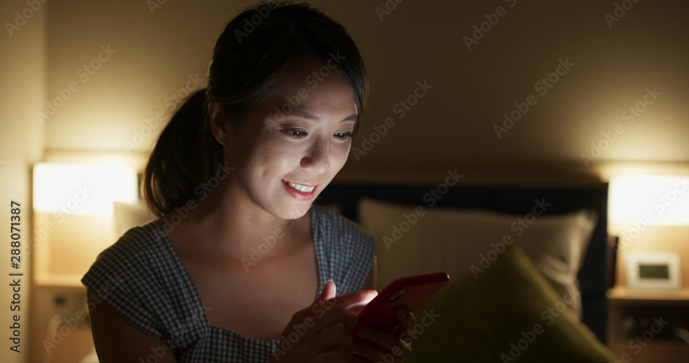 Sticker Woman use of mobile phone on bed at night