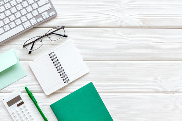 Hipster work desk. Green supplies on white wooden backround flat lay copy space top view