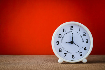white clock at nine o'clock  on grunge wood floor with red background