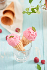 Homemade raspberry ice cream in waffle cones on rustic wooden background, selective focus. Summer time