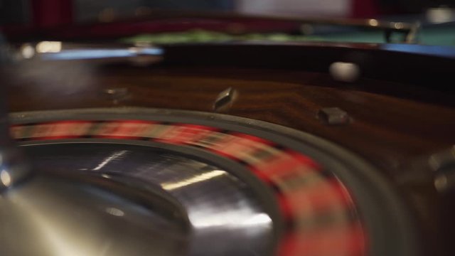 A spinning roulette wheel in a casino with the ball just dropped down spinning and waiting to land on a number.