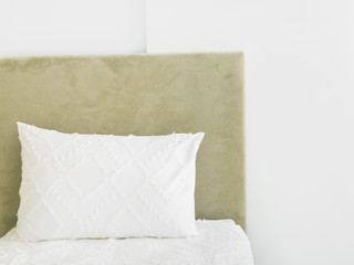 Fragment of bedroom interior in luxurious hotel bed with upholstered velour bedhead board white pillow pure cotton bedlinen wall. Scandinavian minimalist style