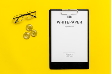 White paper ICO, coins, glasses on yellow background top view