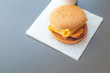 The hamburger was placed on toilet paper. On a gray table in a fast food shop