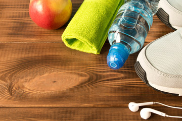 Gray running shoes and fitness accessories on wooden background. Empty text space.