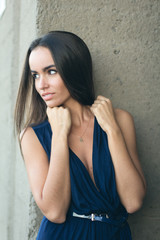 Fototapeta premium portrait of a fashionable woman in a blue dress with a neckline. Industrial wall in the background