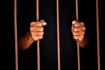 hand man hold steel in jail on black background.concept for prisoner,sadness,detain,erroneousness