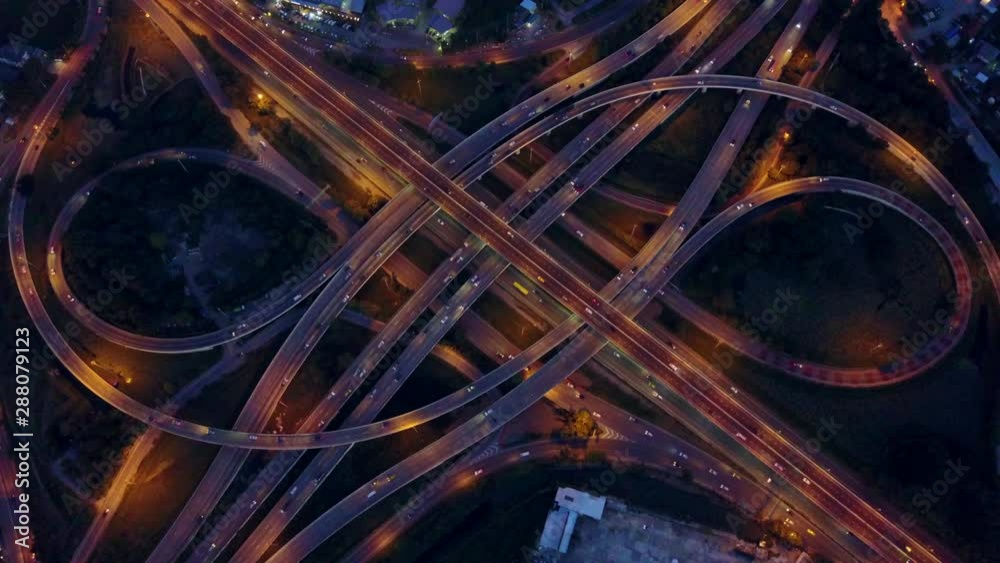 Wall mural 4K. Aerial view of road interchange or highway intersection with busy urban traffic speeding on the road at night. Junction network of transportation taken by drone. - Wall murals