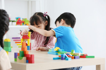 Obraz premium Asian preschool student build block toys at home or daycare. Cheerful kid playing with color cubes. Educational toys for preschool and kindergarten children.