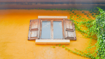 Vintage window with shutters on yellow wall