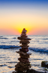 Zen Balancing Pebbles. Stack of pebbles on beach with sunrise on background