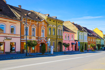 Naklejka premium Sighisoara, Romania, May 11, 2019: Stone paved old street and cafe bar with colorful retro buildings in city center, Sighisoara fortress, Transylvania, Romania, Europe.