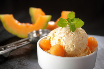 Fresh melon ice cream with melon and melissa on black background