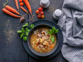 Delicious pea soup with chicken meat and vegetables. Dark plate on a dark wooden background. Top view. Copy space