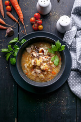 Delicious pea soup with chicken, vegetables and parsley. Dark plate on a dark wooden background. Top view. Vertical shot